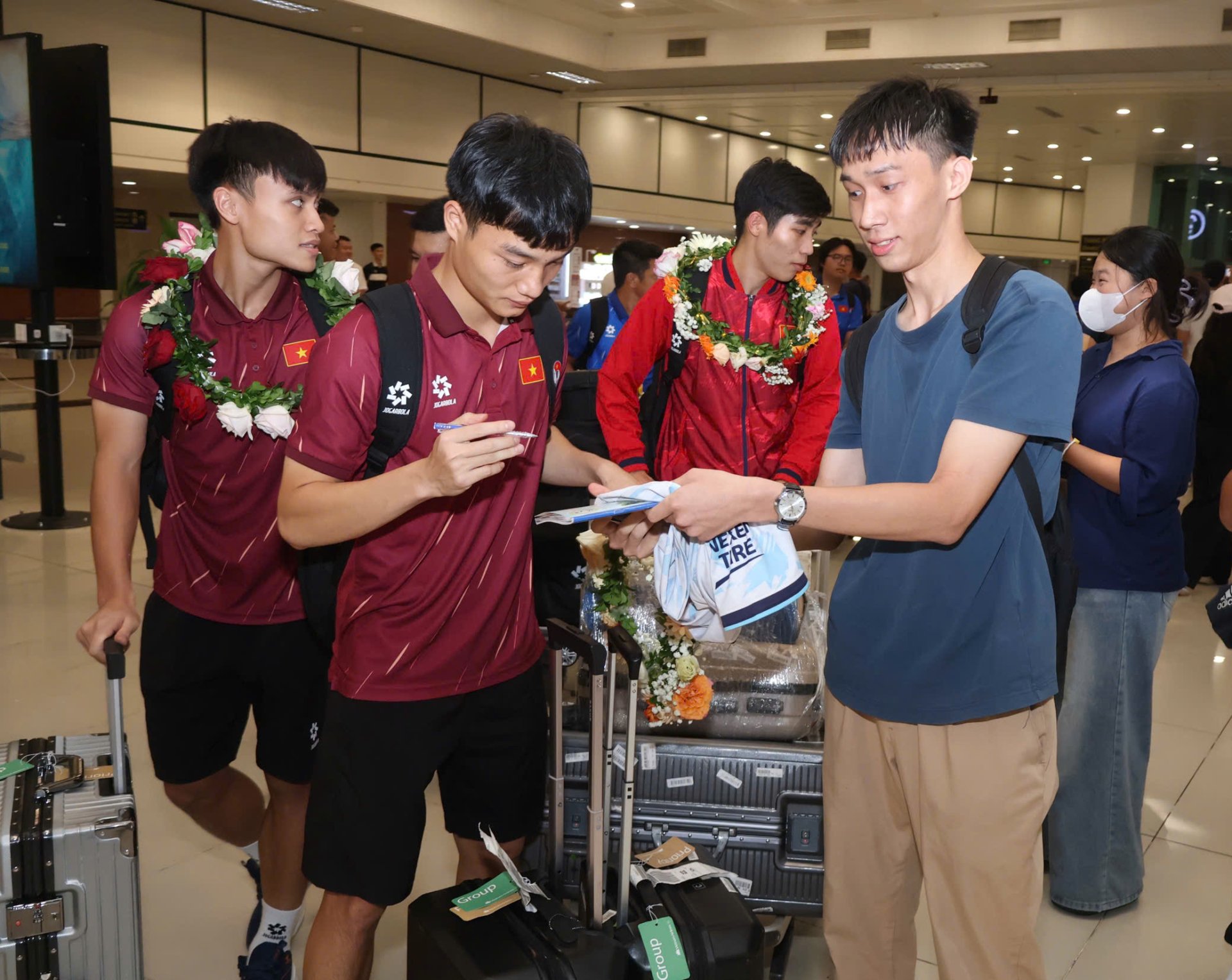 Cầu thủ U23 Việt Nam ký tặng người hâm mộ tại sân bay Nội Bài. Ảnh: Bùi Lượng.
