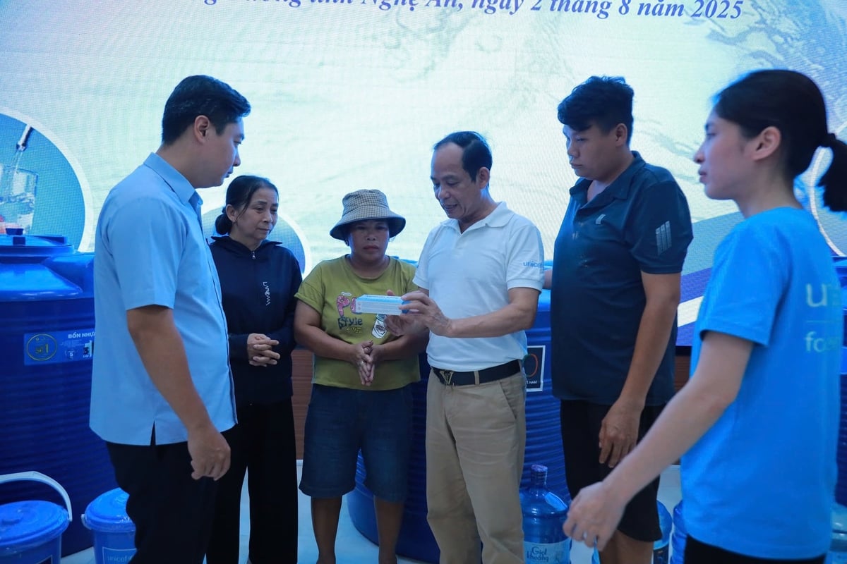 Ông Nguyễn Thành Luân (áo trắng) đang hướng dẫn người dân sử dụng viên khử khuẩn Aquatab. Ảnh: Ngọc Linh.