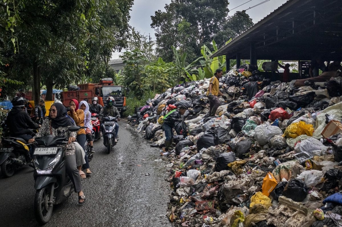 Người dân lái xe chạy ngang qua đống rác tại bãi chôn lấp Cibeber ở thành phố Cimahi, tỉnh Tây Java, Indonesia. Ảnh: Antara/Abdan Syakura.