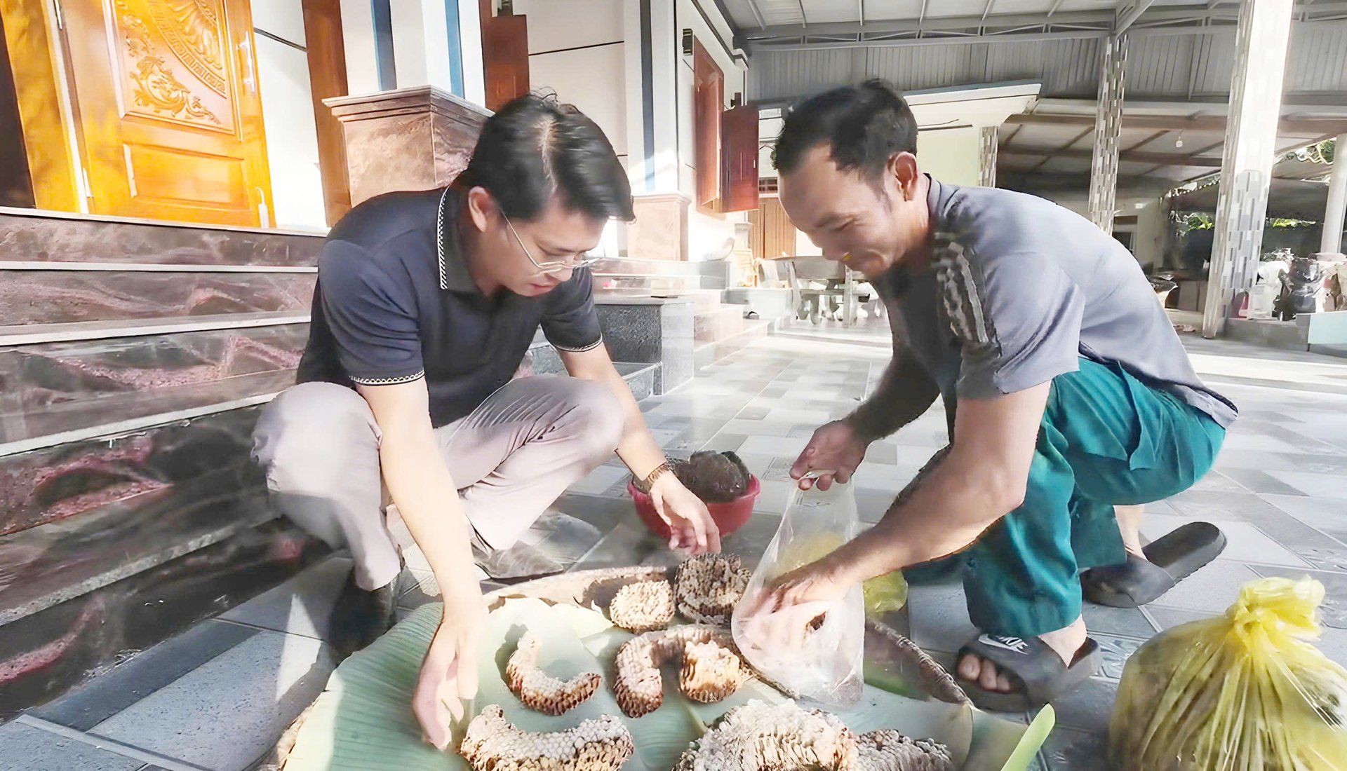 Ông Dũng (bên phải) đang chọn sản phẩm ong vò vẽ cho khách hàng. Ảnh: T. Phùng.