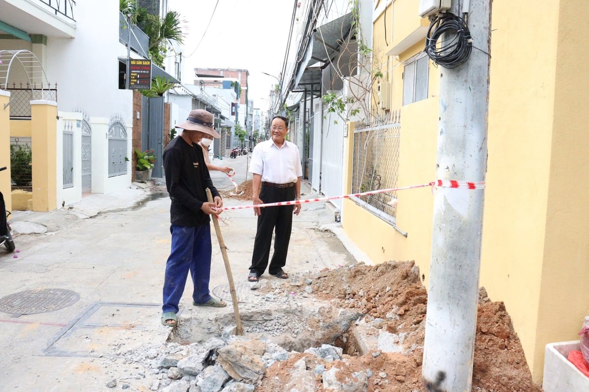 Ông Hồ Bốn, Trưởng ban Công tác Mặt trận khu dân cư Mỹ Tân 1 động viên công nhân làm đường. Ảnh: Lan Anh.