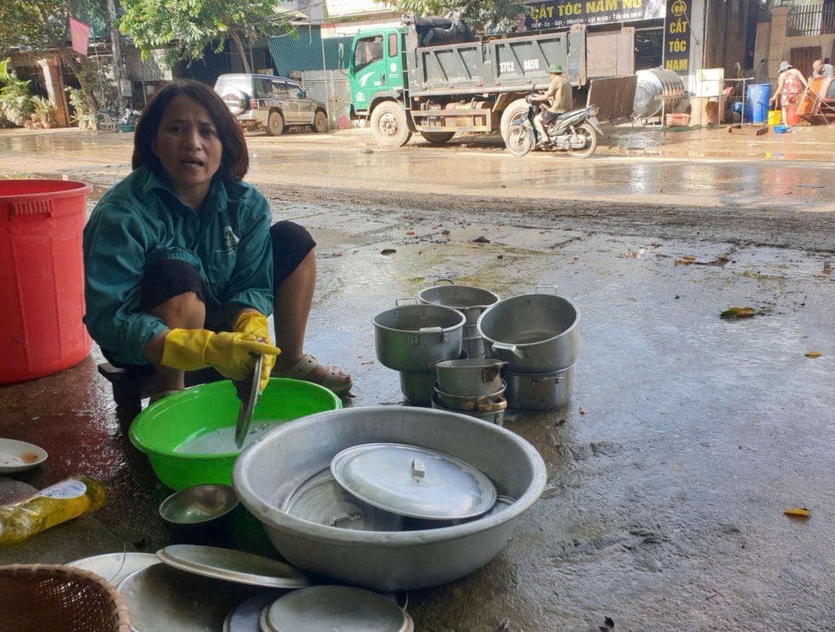 Chị Nguyễn Thị Trà ở Khe Bố kỳ cọ lại từng chiếc nồi, nhặt từng chiếc đũa để nhóm lại bếp gia đình sau lũ dữ. Ảnh: Đình Tiệp.