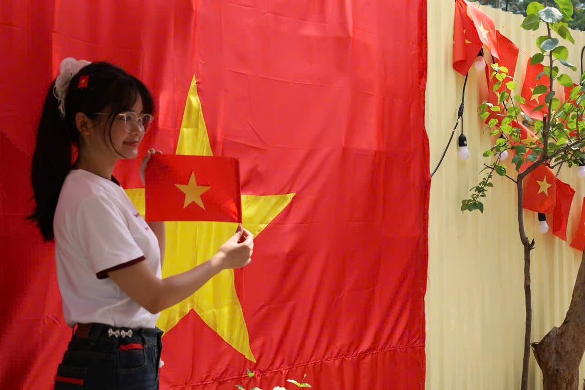 Một bạn trẻ chụp ảnh với lá cờ Tổ quốc cỡ lớn tại một quán cà phê ở dốc La Pho. Ảnh: Hoàng Hiền.