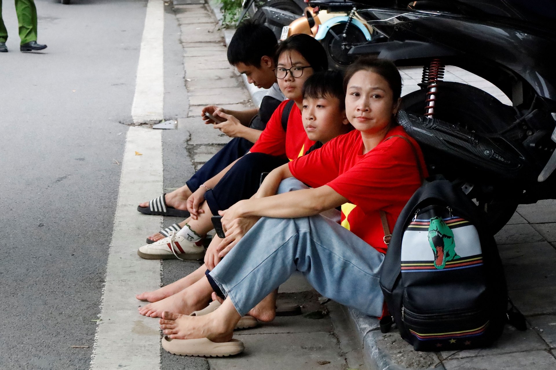Một gia đình ở phường Hoàng Mai ngồi nghỉ bên đường trong 'hành trình' từ 5h sáng. Ảnh: Hoàng Hiền.