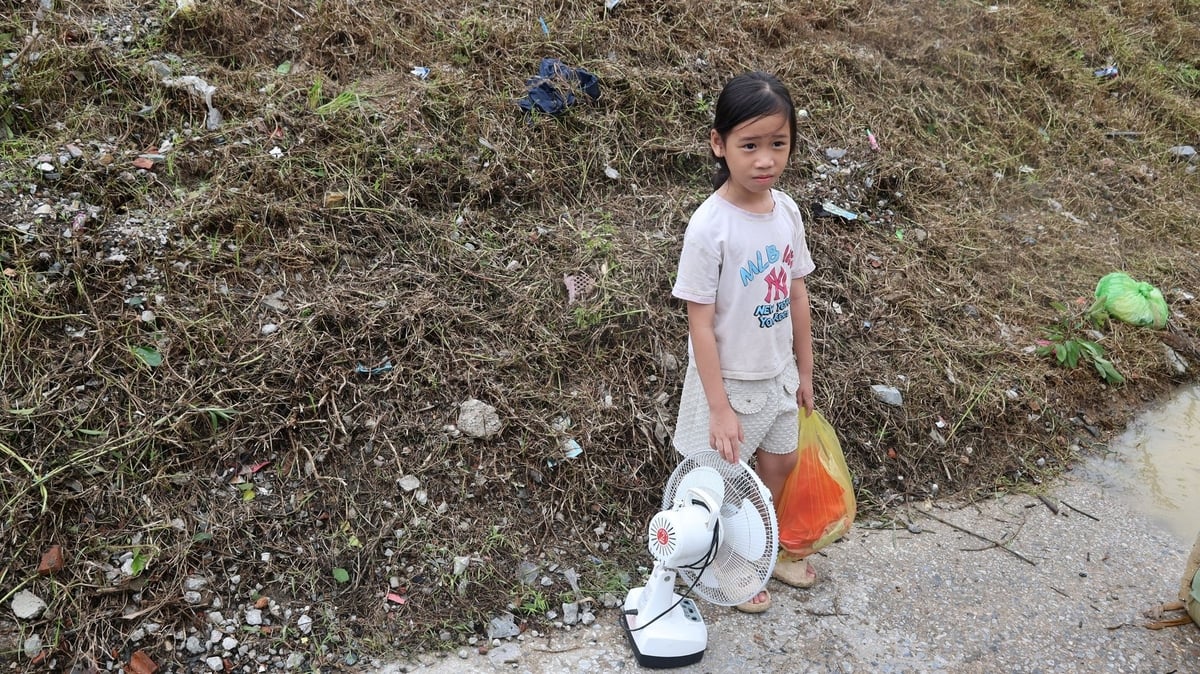 Một em bé theo bố, mang theo quạt tích điện vào sạc nhờ người thân phía trong đê. Ảnh: Thanh Tâm. Một em bé theo bố, mang theo quạt tích điện vào sạc nhờ người thân phía trong đê. Ảnh: Thanh Tâm.