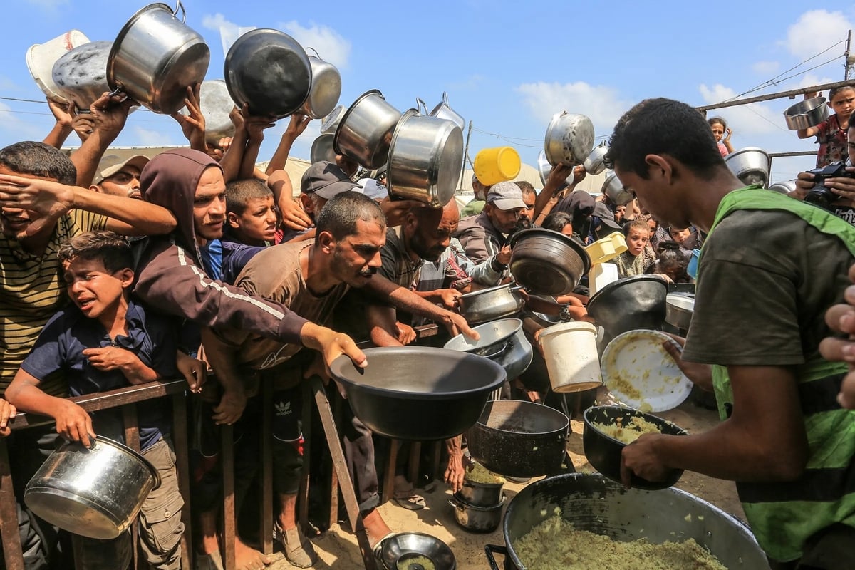 Người dân Palestine, bao gồm cả trẻ em, xếp hàng chờ nhận bữa ăn do tổ chức từ thiện phân phát tại khu vực Al-Mawasi ở Khan Yunis, Gaza, hôm 21/8. Ảnh: Anadolu. Người dân Palestine, bao gồm cả trẻ em, xếp hàng chờ nhận bữa ăn do tổ chức từ thiện phân phát tại khu vực Al-Mawasi ở Khan Yunis, Gaza, hôm 21/8. Ảnh: Anadolu.