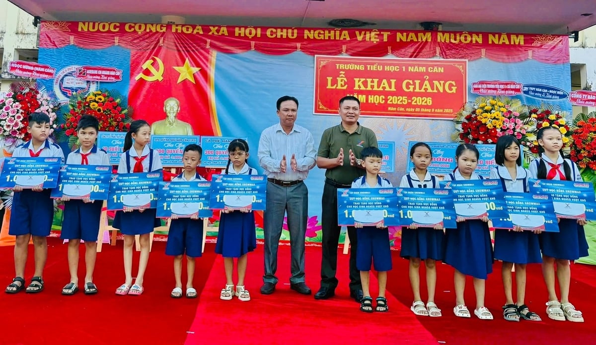 Anh Phùng Hoàng Huy, Trưởng Khu vực Tập đoàn GrowMax trao 10 suất học bổng cho các em học sinh Trường Tiểu học 1 Năm Căn (xã Năm Căn). Ảnh: Trọng Linh.
