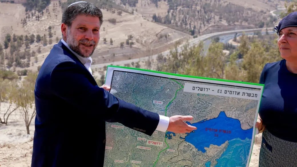 Bộ trưởng Tài chính Israel Bezalel Smotrich cầm bản đồ cho thấy dự án khu định cư E1 trong cuộc họp báo gần khu định cư Maale Adumim ở Bờ Tây hồi tháng 8/2025. Ảnh: Global News. Bộ trưởng Tài chính Israel Bezalel Smotrich cầm bản đồ cho thấy dự án khu định cư E1 trong cuộc họp báo gần khu định cư Maale Adumim ở Bờ Tây hồi tháng 8/2025. Ảnh: Global News.