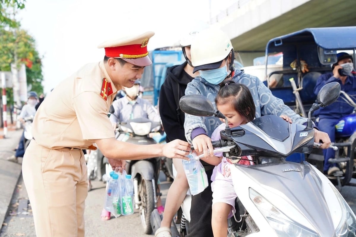 Cảnh sát giao thông ở các cửa ngõ thành phố vừa điều tiết giao thông, vừa phát nước cho người dân. 