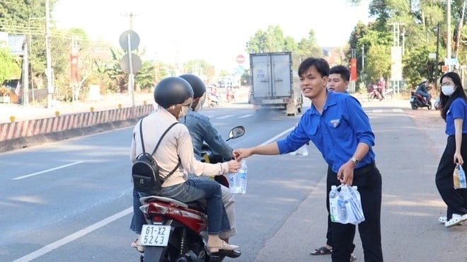 Đoàn viên, thanh niên tặng nước đóng chai cho người dân về Đồng Nai ăn Tết hòng bớt đi cái khát trên lộ trình và bớt chút chi phí bán mua. Ảnh: Dương Huynh.