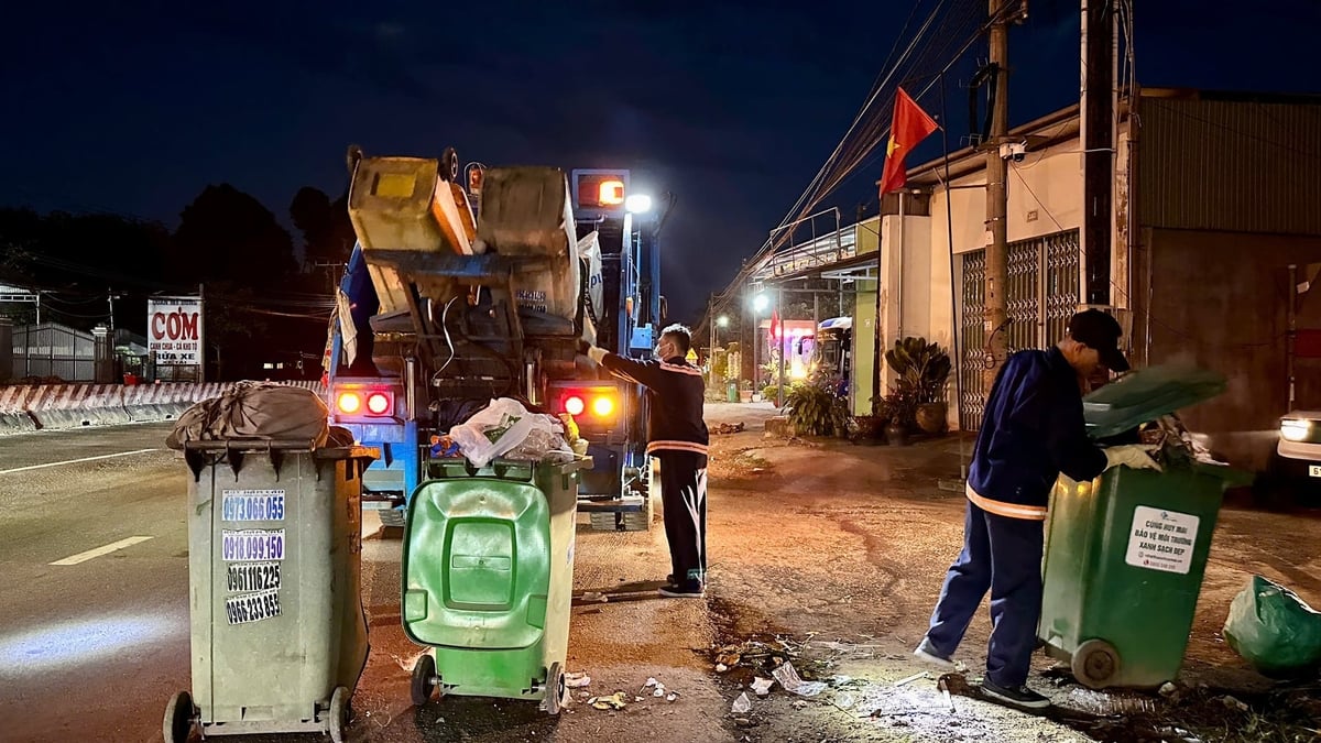 Giữa đêm khuya, công nhân Đội vệ sinh miệt mài thu gom rác lên xe chuyên dụng. Ánh đèn vàng hắt xuống những đôi tay chai sạn, nơi mùa xuân bắt đầu từ sự thầm lặng và trách nhiệm. Ảnh: Minh Duy.