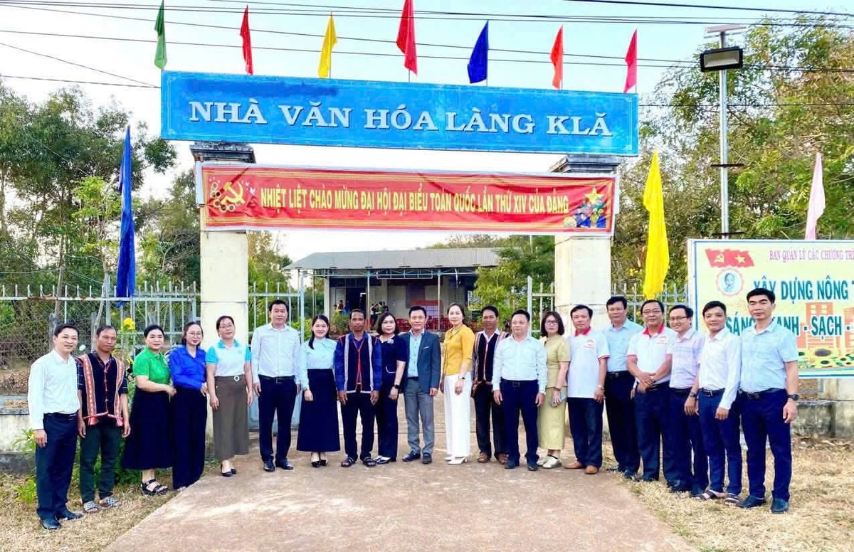 Cán bộ 2 địa phương kết nghĩa chụp ảnh lưu niệm trước Nhà Vă hóa làng KLă. Ảnh: Bảo Sương.