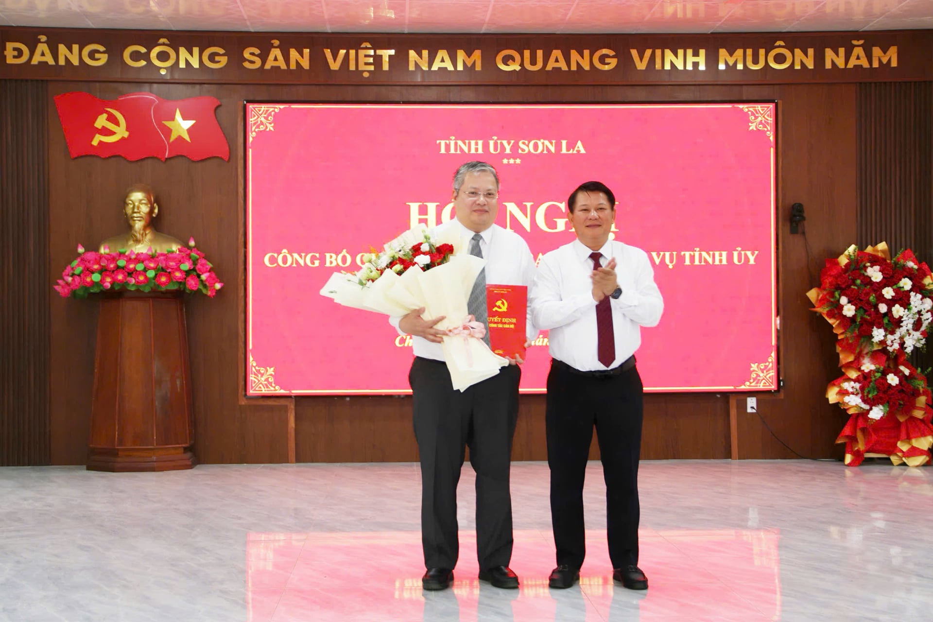 Ông Lò Minh Hùng, Phó Bí thư Thường trực Tỉnh ủy, Chủ tịch HĐND tỉnh Sơn La trao quyết định, tặng hoa chúc mừng ông Phùng Kim Sơn. Ảnh: Nguyễn Nga.