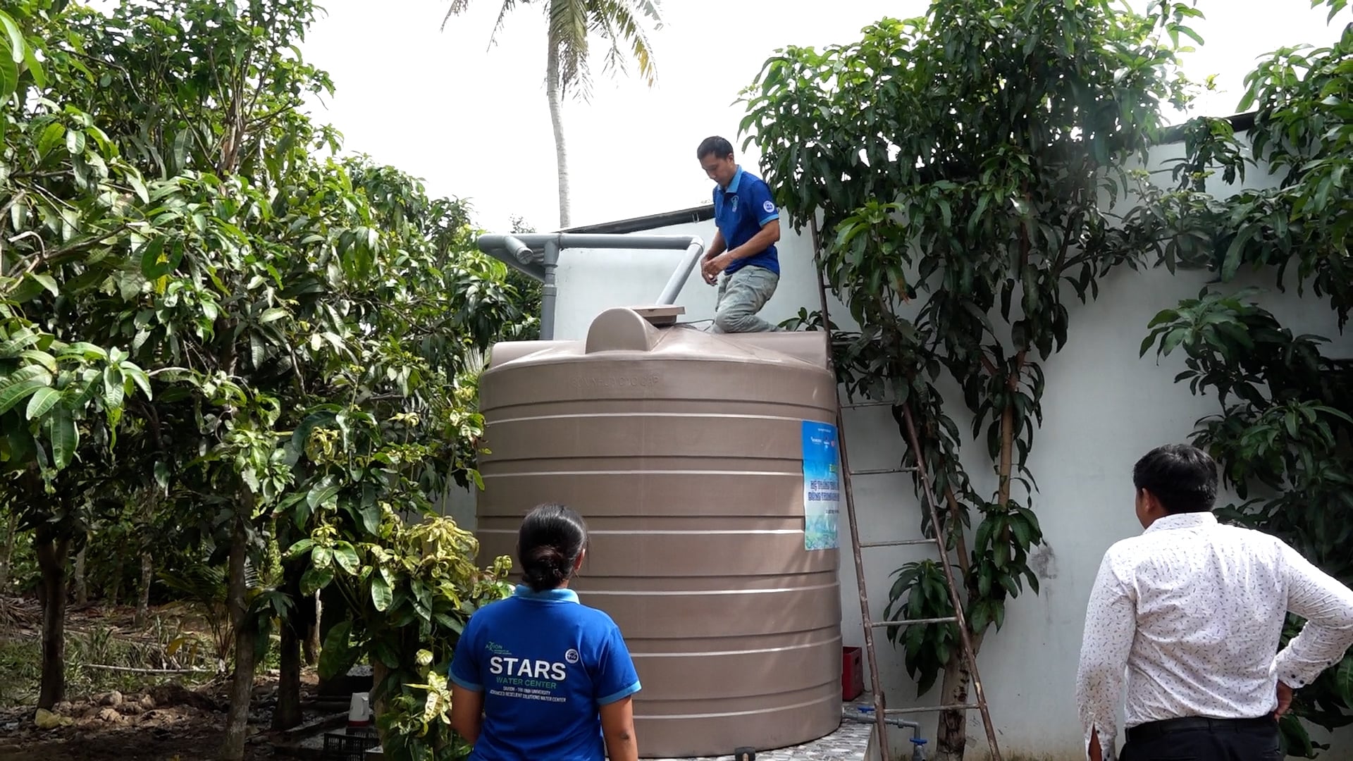 Cán bộ kỹ thuật đang lắp đặt hệ thống trữ nước mưa cho người dân. Ảnh: Hồ Thảo.