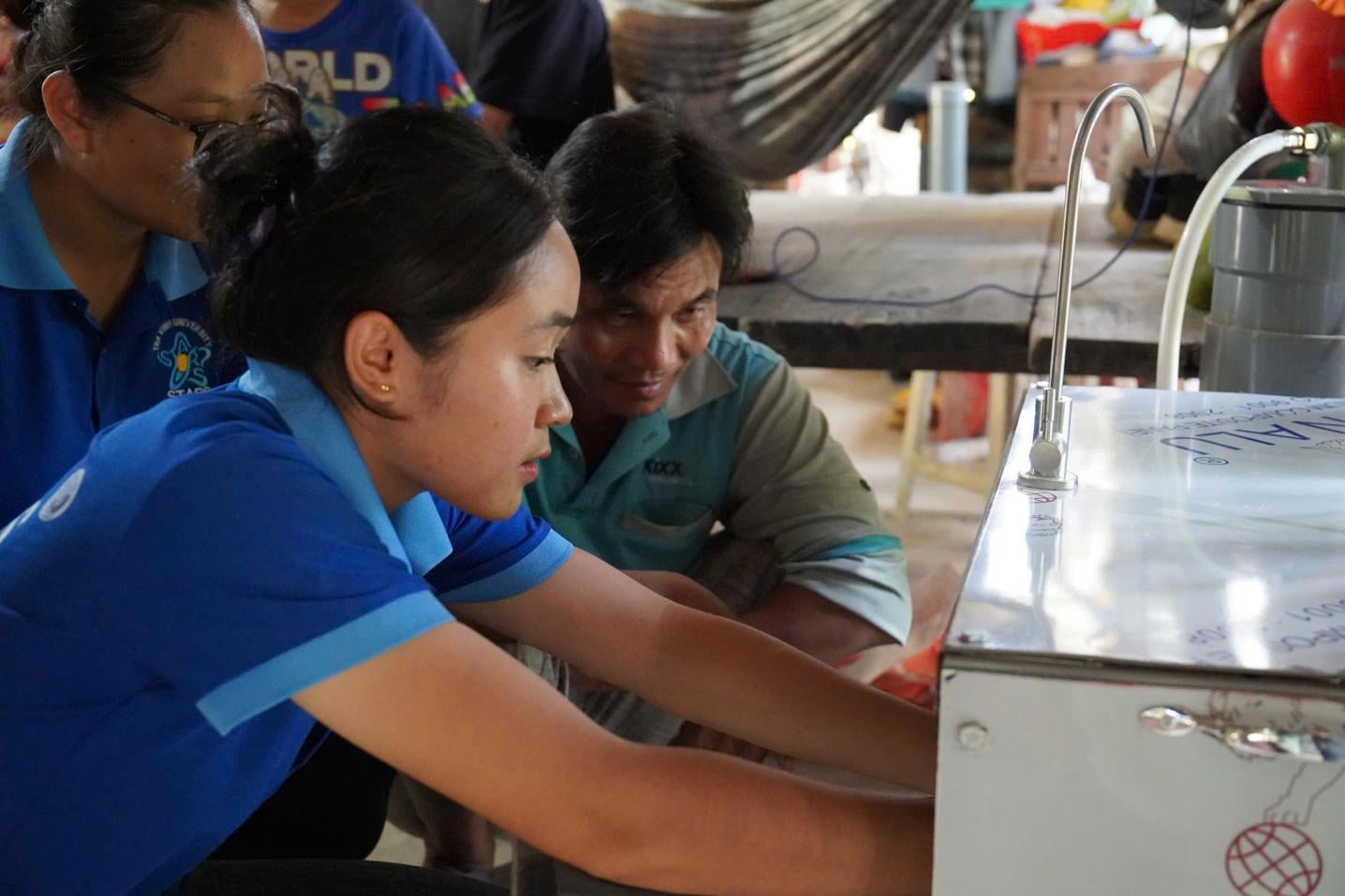 Cán bộ Trung tâm Nước hướng dẫn người dân sử dụng hệ thống thu trữ và xử lý nước mưa. Ảnh: Hồ Thảo.