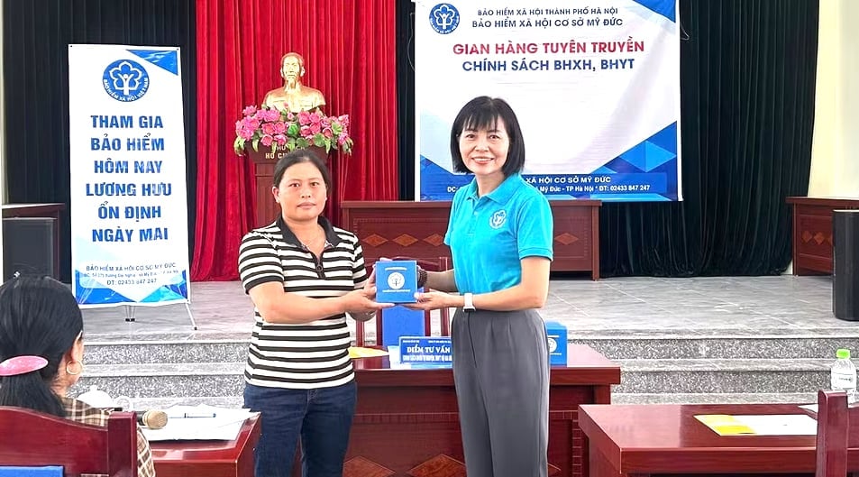 Cán bộ Bảo hiểm xã hội TP. Hà Nội trao hỗ trợ cho người dân. Ảnh: HSS.