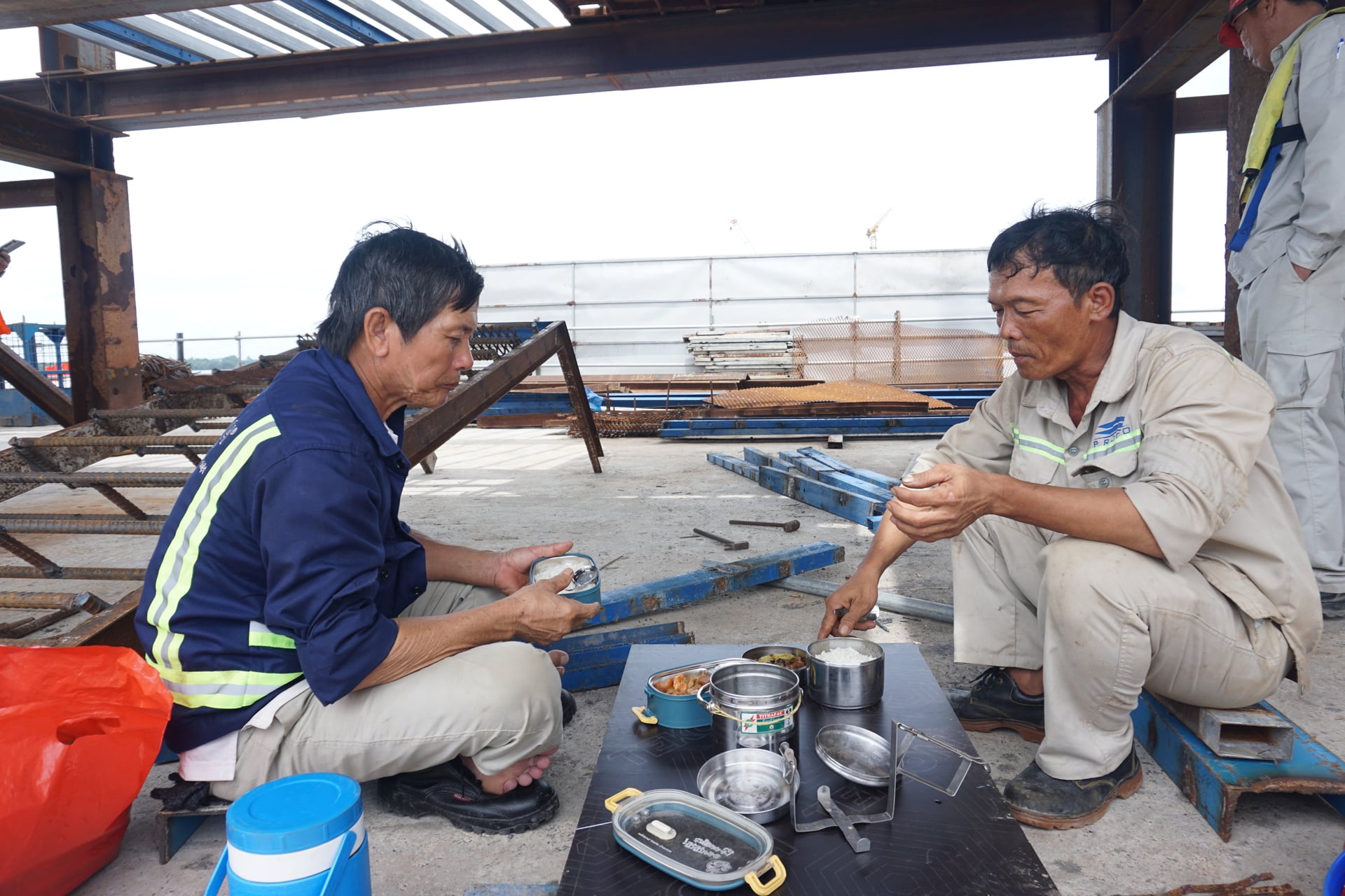 Ông Hào (phải) dùng bữa trưa và nghỉ ngơi tại công trường trước khi vào ca làm việc buổi chiều. Ảnh: HT.