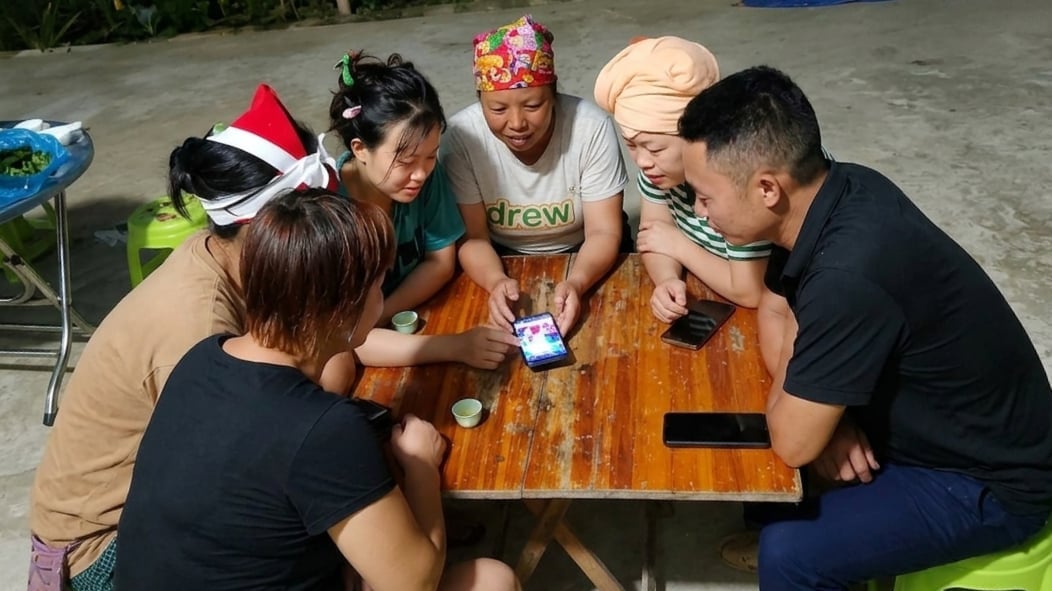Trưởng bản thời đại 4.0 Tẩn Sành Phú, thôn Lũng Pô, xã A Mú Sung, Lào Cai (áo đen ngoài cùng bên phải) đang hướng dẫn người dân cài đặt các ứng dụng cần thiết, sử dụng tài khoản định danh điện tử VNeID... trên điện thoại thông minh. Ảnh: Bích Hợp.