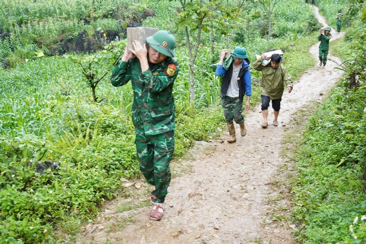 Cán bộ xã hỗ trợ mang vật liệu vào xây dựng căn nhà của bà Đào Thị Sinh. Ảnh: Ngọc Tú.