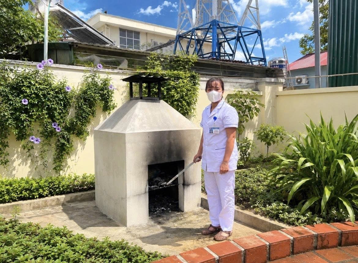 Bà Thái Thị Mai, điều dưỡng Trạm Y tế xã Thanh Nưa, tỉnh Điện Biên thực hiện xử lý chất thải y tế tại lò đốt của đơn vị theo quy trình chuyên môn. Ảnh: Nguyễn Yến. 