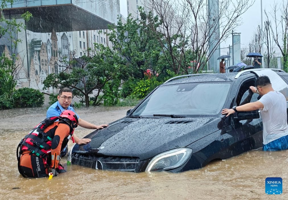 Cảnh sát và lực lượng cứu hỏa hỗ trợ giải cứu một ô tô bị mắc kẹt tại thành phố Thẩm Dương, tỉnh Liêu Ninh vào ngày 13/7. Ảnh: Tân Hoa Xã.