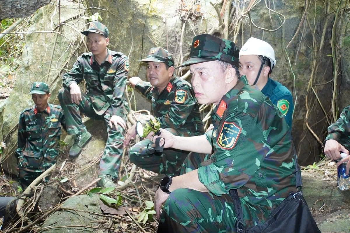 Lực lượng chức năng cẩn trọng tìm kiếm, cất bốc hài cốt liệt sĩ trong hang Đá Sập, xã Hà Nha. Ảnh: Quang Cường.