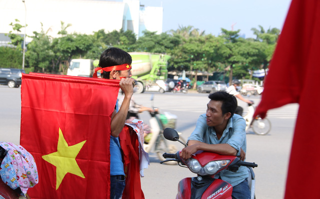 Một thanh niên bán cờ Tổ quốc lang thang khắp trước cửa sân Mỹ Đình mà chưa bán được lá cờ nào.