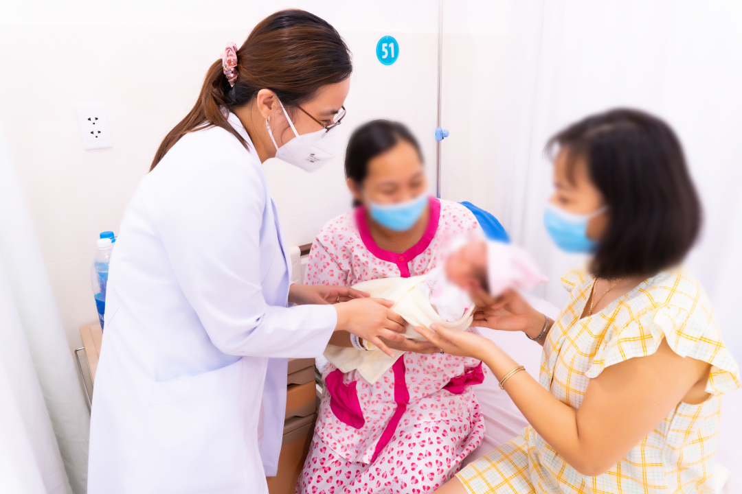 Bé gái chào đời từ phương pháp mang thai hộ, trong vòng tay của hai người mẹ. Ảnh: Bệnh viện cung cấp.