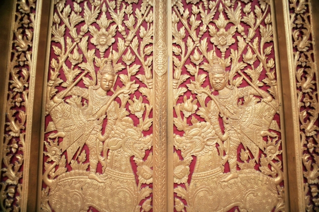 Chính điện có bốn cổng được làm bằng gỗ – nguyên thân gỗ xẻ, khắc cảnh giao đấu giữa hai nhân vật thiện – ác trên nền khung được trang trí hoa văn tinh xảo, thể hiện trình độ chạm khắc gỗ cao của các nghệ nhân.