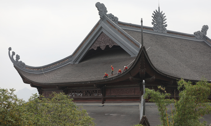 Nhóm công nhân làm việc trên phần mái của một gian chùa.