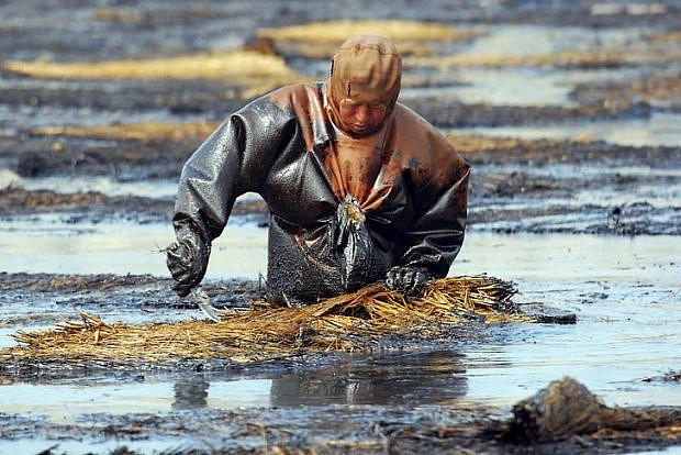Hình ảnh một nhân viên đang cố gắng làm sạch nước do một vụ tràn dầu lớn xảy ra ở Dalian, Trung Quốc vào năm 2010 khi gần 250 đường ống dẫn dầu bị phát nổ khiến cho một lượng lớn dầu bị tràn và lan rộng ra đến hơn 500 mét vuông diện tích nước biển.
