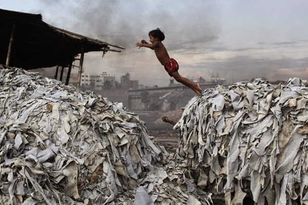 Một cô bé nghịch ngợm nhảy từ bãi rác này sang bãi rác kia ở Dhaka, Bangladesh. Rác thải còn được sử dụng làm thức ăn cho gia súc, gia cầm nuôi trong nhà.