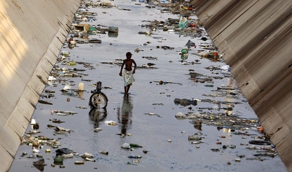 Cậu bé này đang đi qua một con kênh ô nhiễm ở Benguela, Angola.