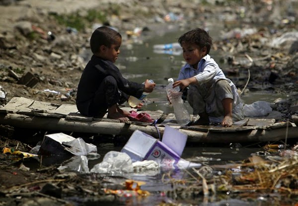 Hai cậu bé chia sẻ với nhau chai nước bẩn bên cạnh vũng nước ô nhiễm, đầy rác thải ở Kabul, Afghanistan.