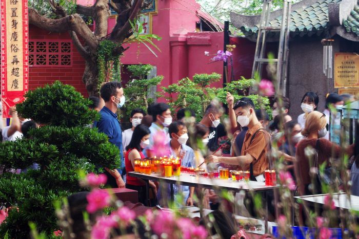Will Horton (áo xanh phía trái) đang đợi bạn gái châm nhang ở chùa. Tết năm nay, anh ở lại thành phố, đi chúc Tết gia đình bạn gái và cùng cô ấy du xuân. Ảnh: Ý Linh.