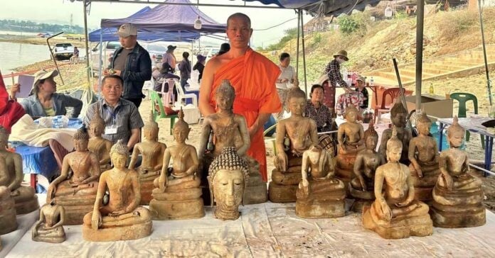 Một nhà sư chụp ảnh với những tượng Phật mới được tìm thấy ở Lào. (Nguồn: Laotian Times)