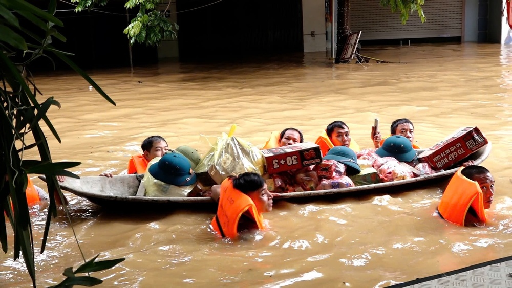 Sau khi chở người dân ra khỏi vùng lũ, bộ đội lại dầm mình đẩy thuyền chở theo cơm, lương thực, thực phẩm, nước ngọt vào cho những người ở lại. Ảnh: Báo VnExpress.