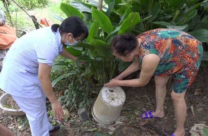 Hướng dẫn người dân dọn vệ sinh môi trường diệt nơi trú ẩn của muỗi. Ảnh: BLC