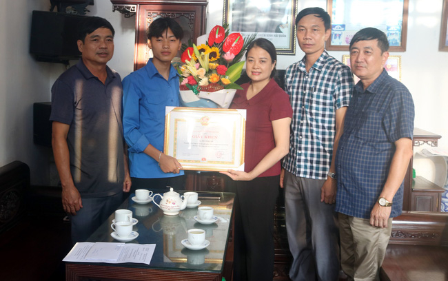 Lãnh đạo UBND huyện Hải Hậu trao giấy khen cho em Bùi Hải An (thứ 2, từ trái sang). Ảnh: TTXVN