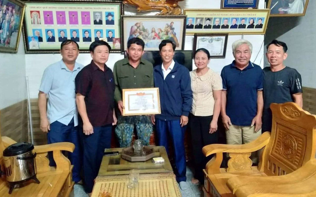 Đại diện Đảng ủy, UBND xã Thanh Liên tặng Giấy khen anh Trần Văn Tiến (người thứ 3 bên trái sang). Ảnh: TTXVN
