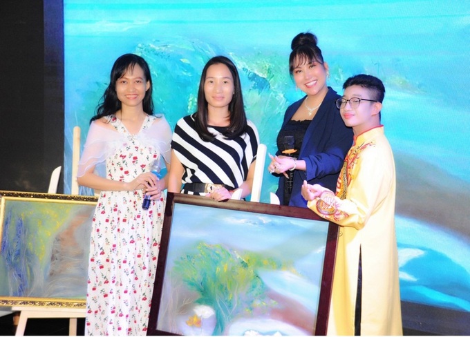 Doanh nhân Lê Thị Thanh Tâm (chính giữa bên trái) là người mua đấu giá thành công bức tranh “Năng lượng xanh quê hương” của tác giả Đỗ Thiên Hương