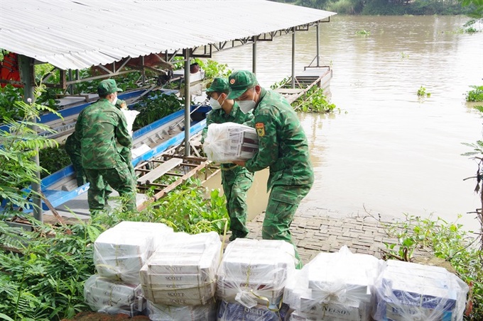 Tổ công tác của Đồn Biên phòng Cầu Muống chuyển tang vật buôn lậu lên bờ. Ảnh: Phú Quý/Báo Biên phòng