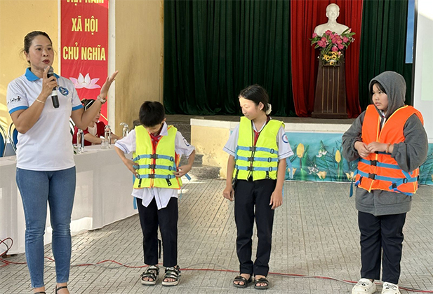 Hướng dẫn cách mặc áo phao an toàn cho các em học sinh. Ảnh: Thuathienhue.gov