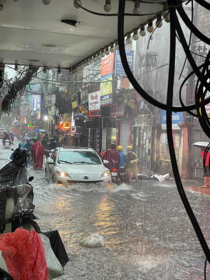 Tại phố Triều Khúc, nước ngập sâu, xe ô tô con đi nhanh khiến xe máy đi gần đó bị ngã xuống đường  