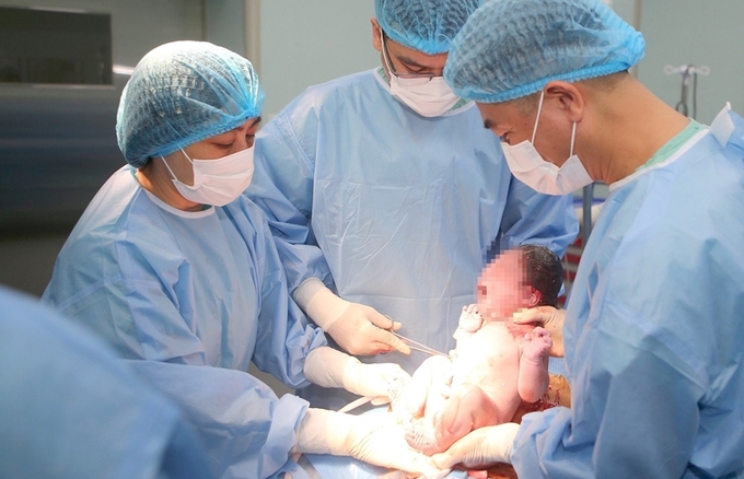 :  Nữ hộ sinh hỗ trợ chăm sóc trẻ sau một ca sinh tại BV Trưng ương Huế