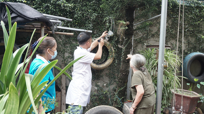 Cán bộ y tế quận Long Biên hướng dẫn người dân tìm diệt bọ gậy. Ảnh; Hà Nội mới