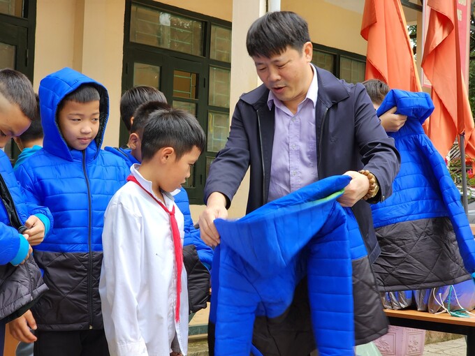 Nhà báo Xuân Hùng (Báo Lao động) đại diện đơn vị tài trợ trao áo ấm cho các em học sinh