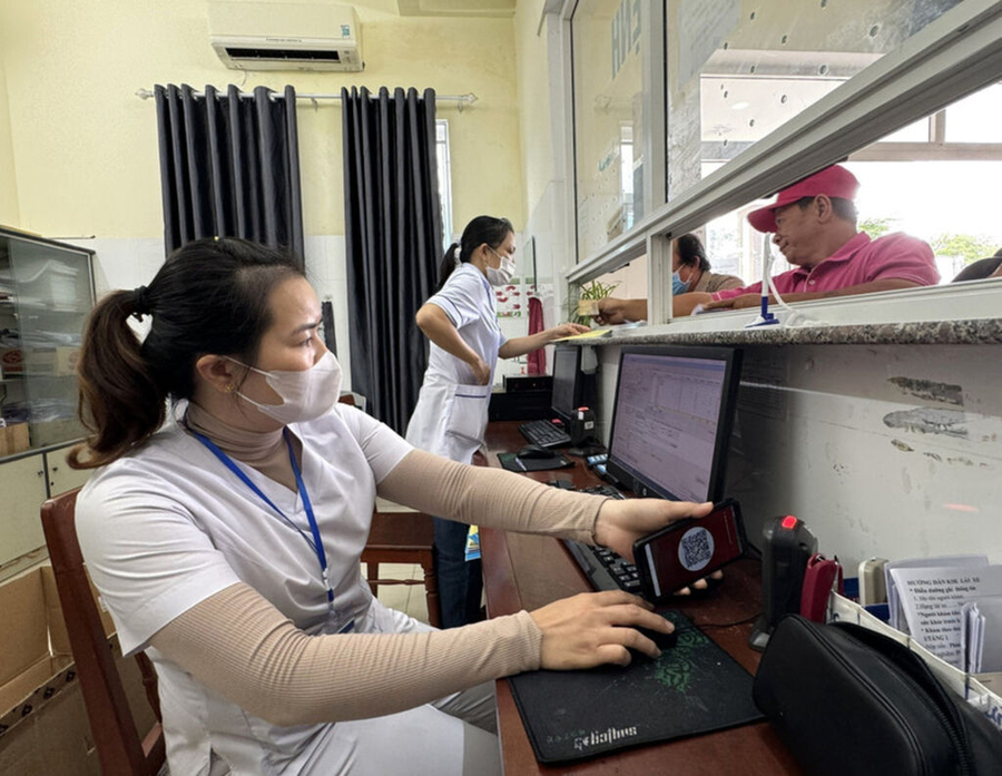 Nhân viên y tế quét mã lấy số và đăng ký khám bệnh tại các ki-ốt phát số tự động.   Ảnh: Đinh Hương - TTXVN