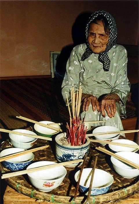 Hình ảnh mẹ Nguyễn Thị Thứ bên mâm cơm với 9 cái bát, 9 đôi đũa dành cho 9 người con của mình