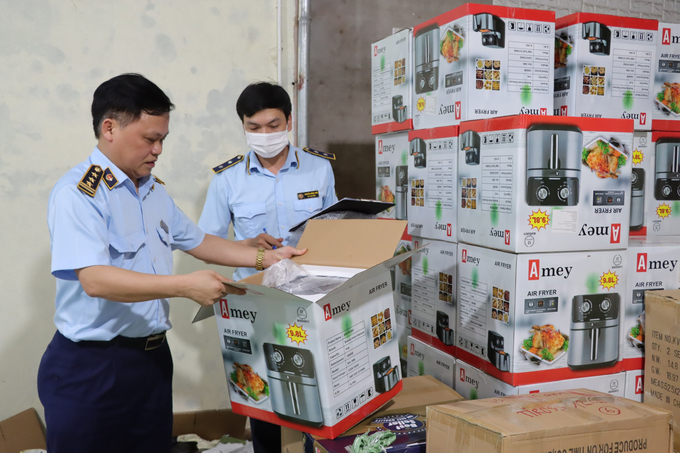 Ông Nguyễn Văn Hùng - Quyền Cục trưởng Cục QLTT tỉnh Thanh Hóa (trái) đi kiểm tra số lượng sản phẩm nghi là hàng giả bán qua mạng xã hội.